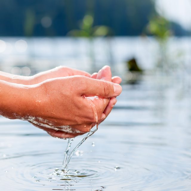 Hände mit Wasser aus klarem Bergsee.